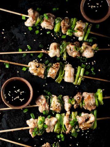 yakitori on a platter with sauce bowls and sesame seeds