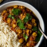 chickpea curry in a bowl with rice and cilantro