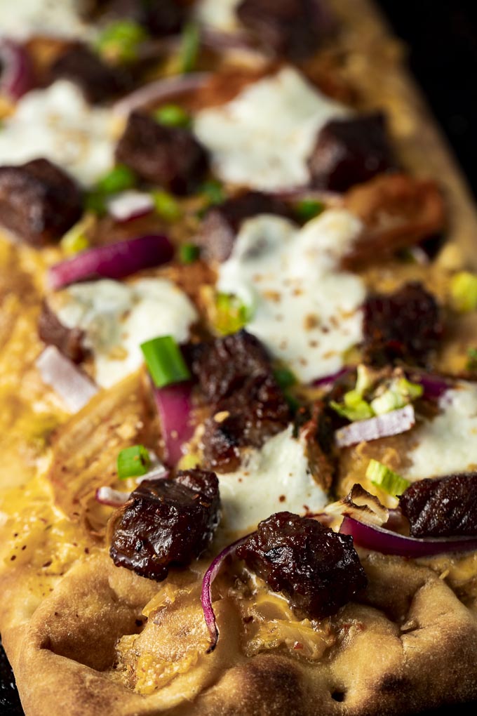 pizza crust baked and topped with beef, kimchi, onions and cheese
