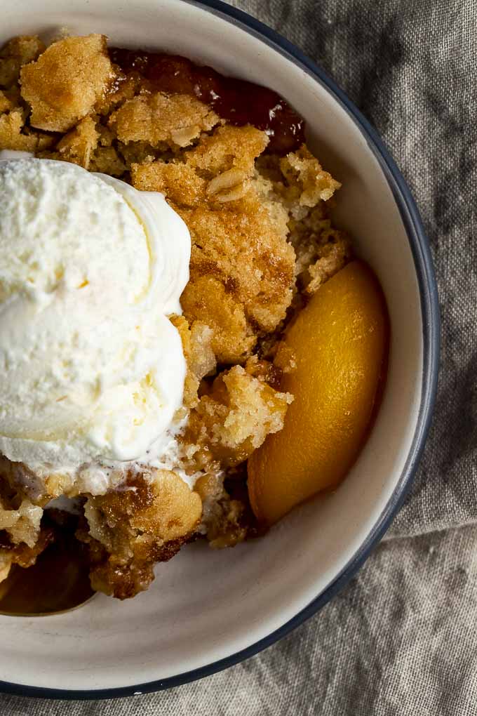 bowl of peach cobbler with ice cream on top - close up photo