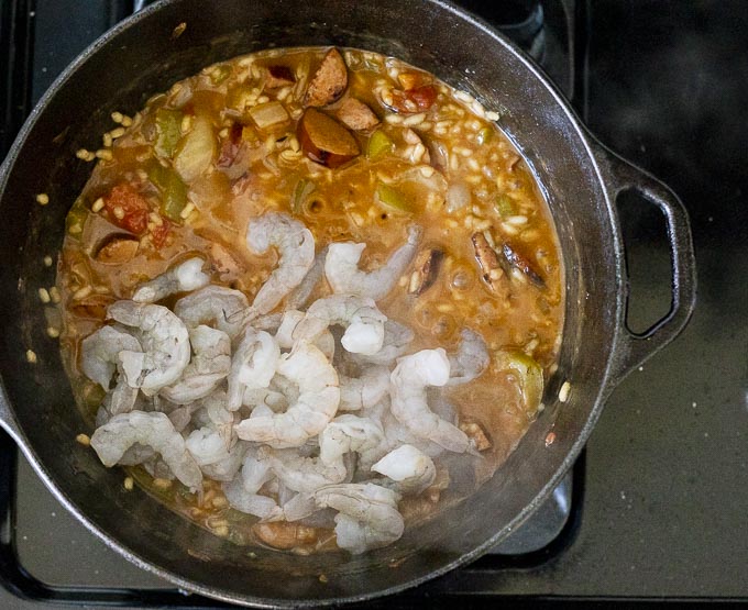 raw shrimp added to a pot of rice and vegetables