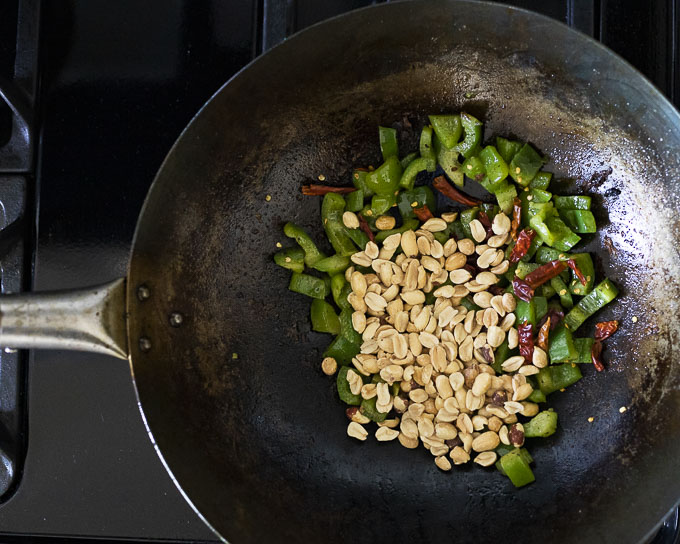 green peppers, chilies and peanuts in a wok
