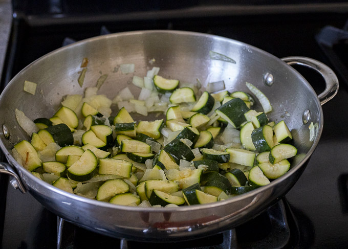 zucchini and onions cooking in a skillet