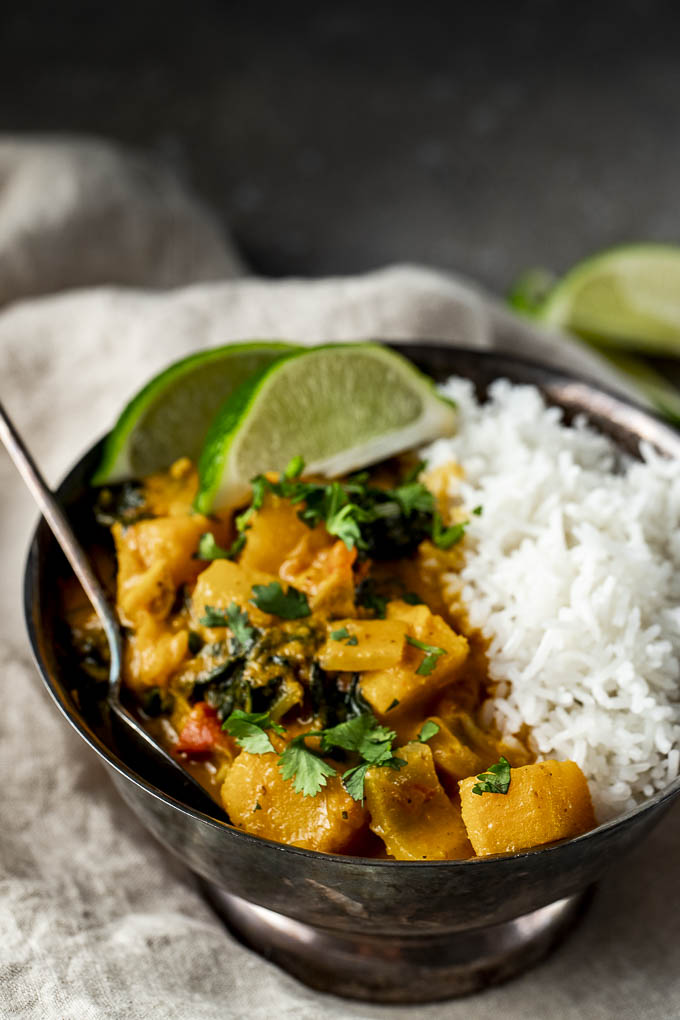 cubed butternut squash in an orange curry sauce with rice in a bowl