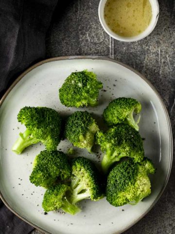 broccoli on a plate with lemon butter on the side