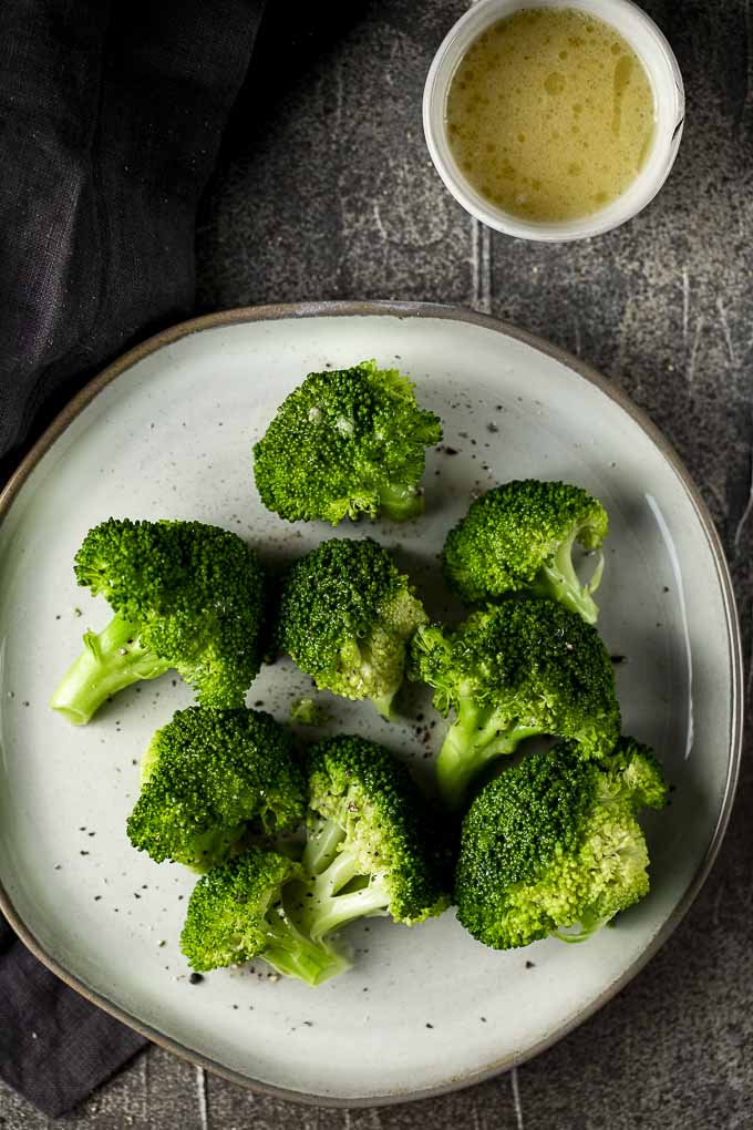 broccoli on a plate with lemon butter on the side