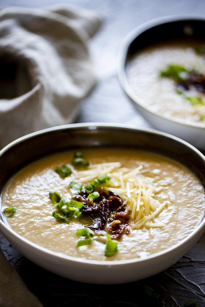 bowls of creamy pureed cauliflower soup with bacon and green onions