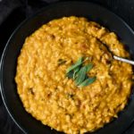 bowls of orange colored risotto with sage leaves