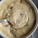 a bowl of white cream gravy with bacon in it