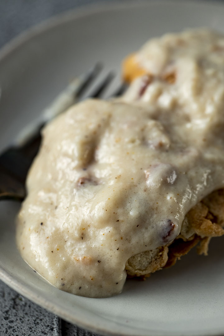 white gravy on top of biscuits on a plate