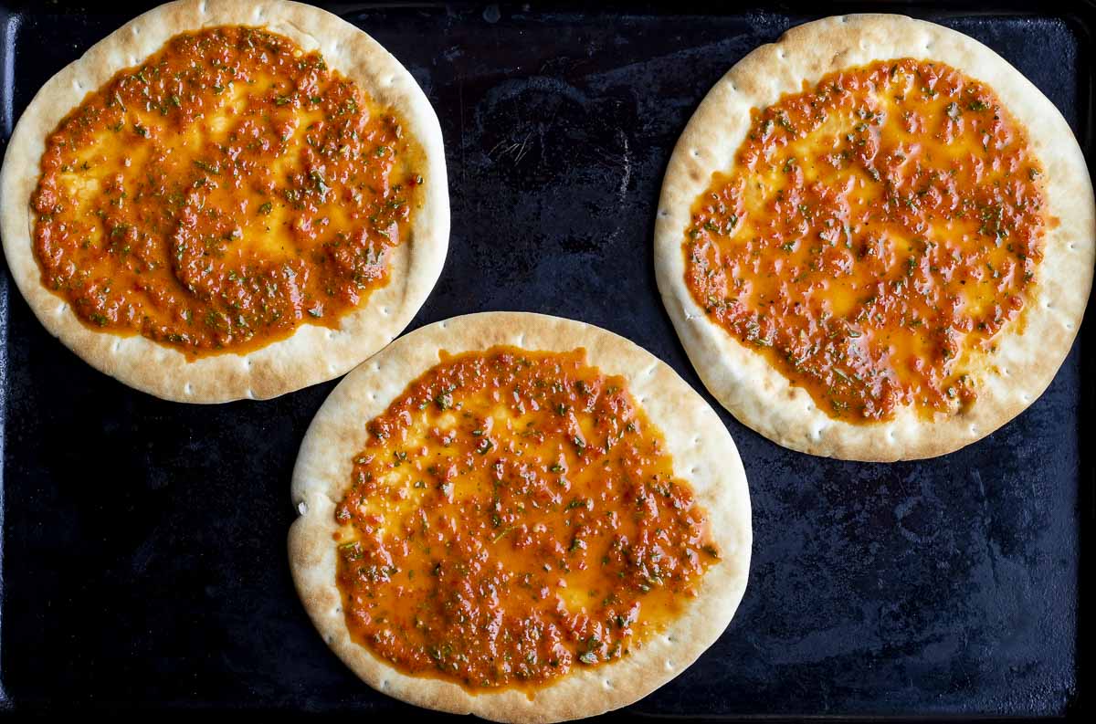 3 pita breads covered in a red sauce
