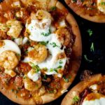 pita pizza topped with cheese, parsley, shrimp and a red sauce
