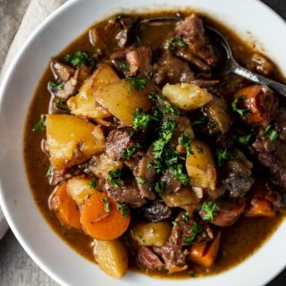 bowl of beef, potatoes and carrots in a brown broth