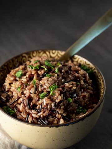 a bowl of wild rice with a gold spoon in it