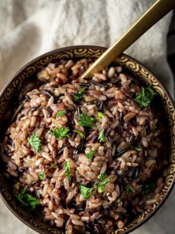 wild rice in a bowl with parsley and a spoon