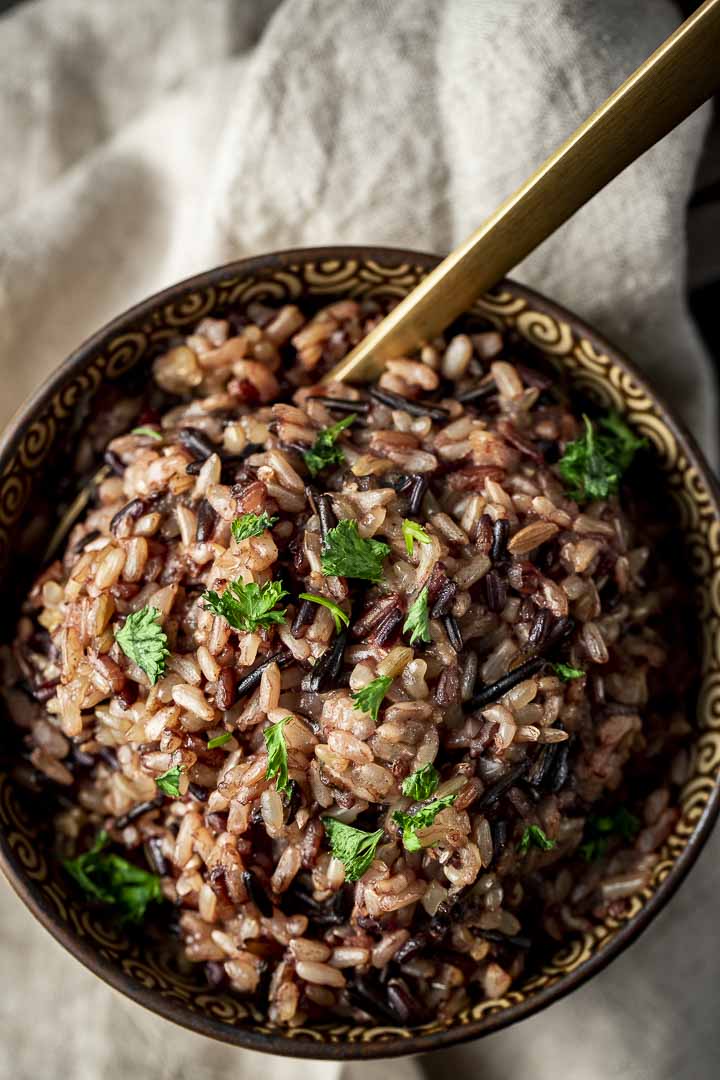 wild rice in a bowl with parsley and a spoon