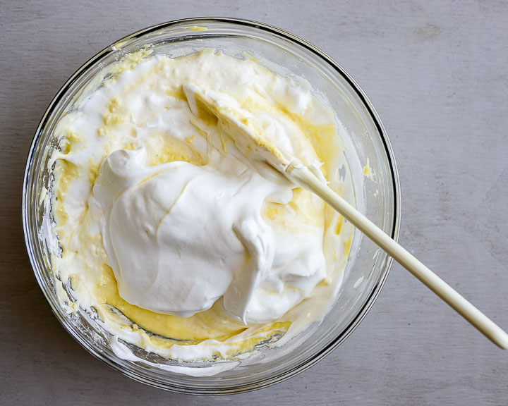 whipped egg whites being folded into yellow batter