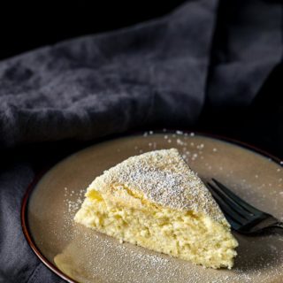a piece of yellow cake dusted with powdered sugar with a fork