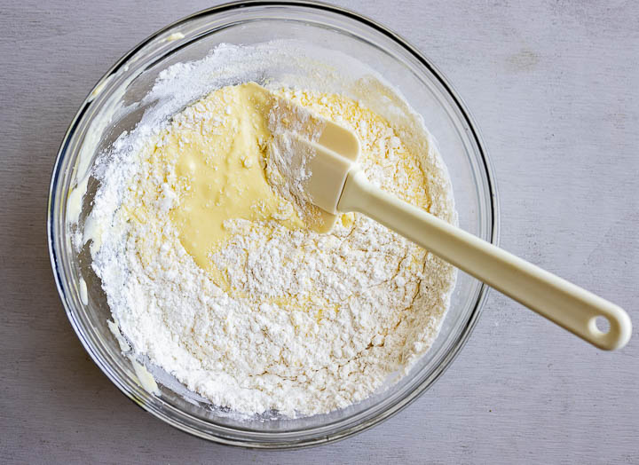 flour being stirred into a yellow batter