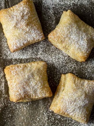 4 pastries covered in powdered sugar on parchment paper