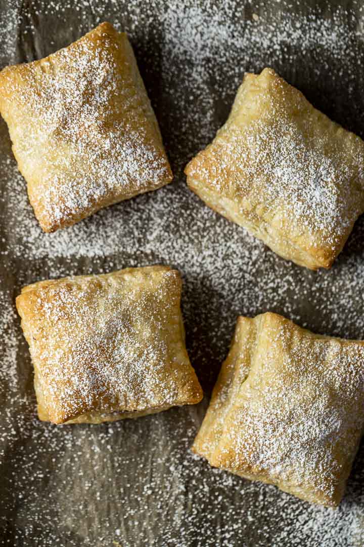 4 pastries covered in powdered sugar on parchment paper