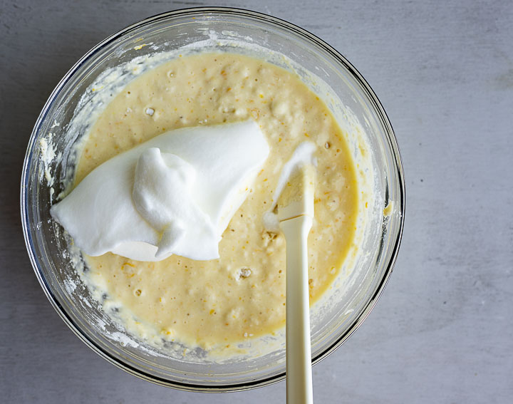 yellow batter being mixed with whipped egg whites