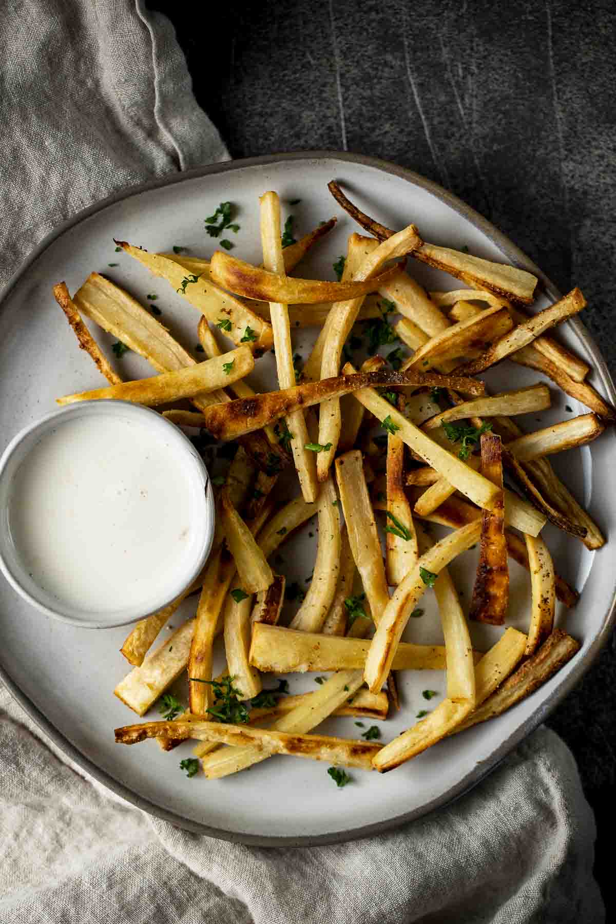 a plate of fries with white dipping sauce on the side