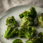 roasted broccoli crowns on a plate sprinkled with pepper