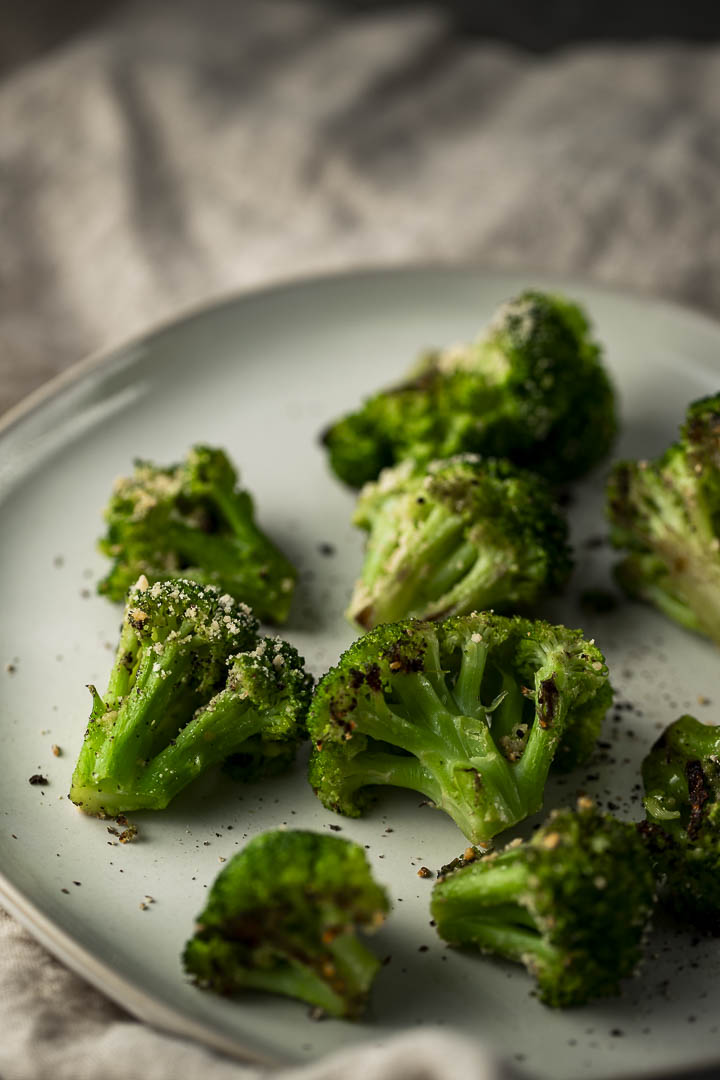 roasted broccoli crowns on a plate sprinkled with pepper