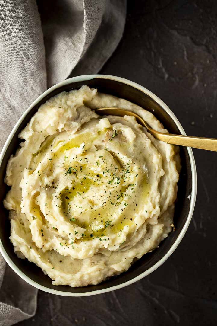 a bowl of creamy mashed potatoes with a gold spoon