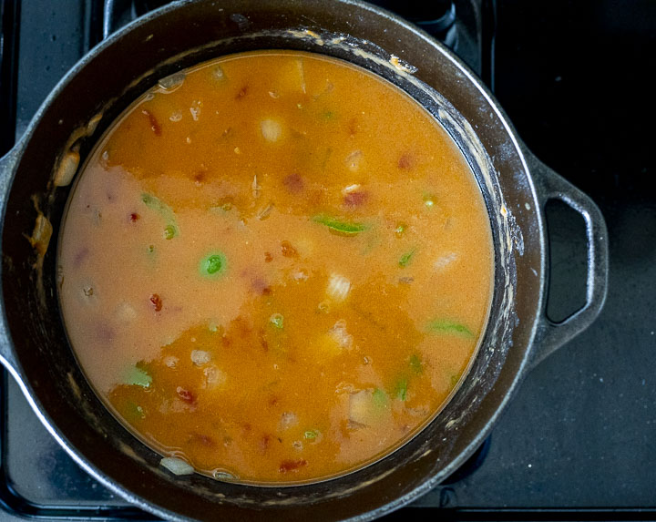 orange liquid in a pot with green peppers and onions