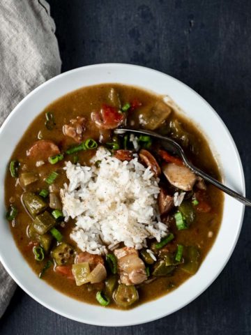 bowl of gumbo with white rice in the middle and a spoon
