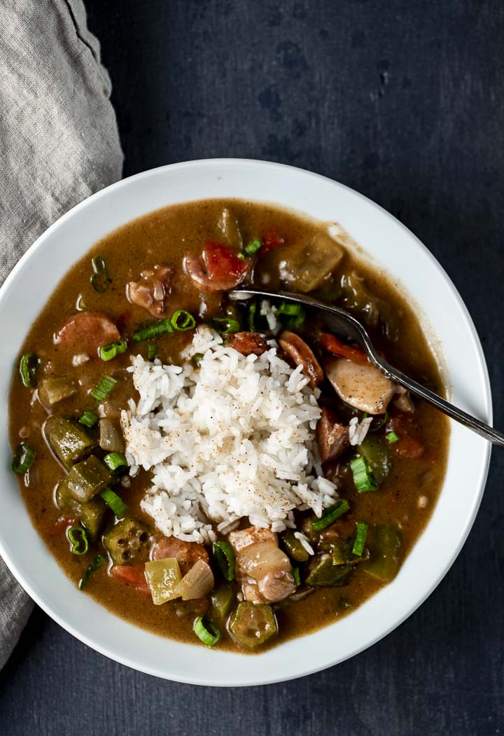 bowl of gumbo with white rice in the middle and a spoon