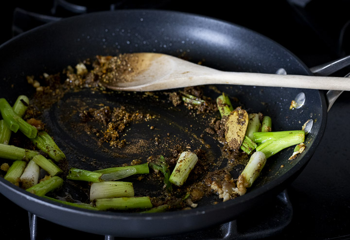 spices and green onions cooking in a skillet