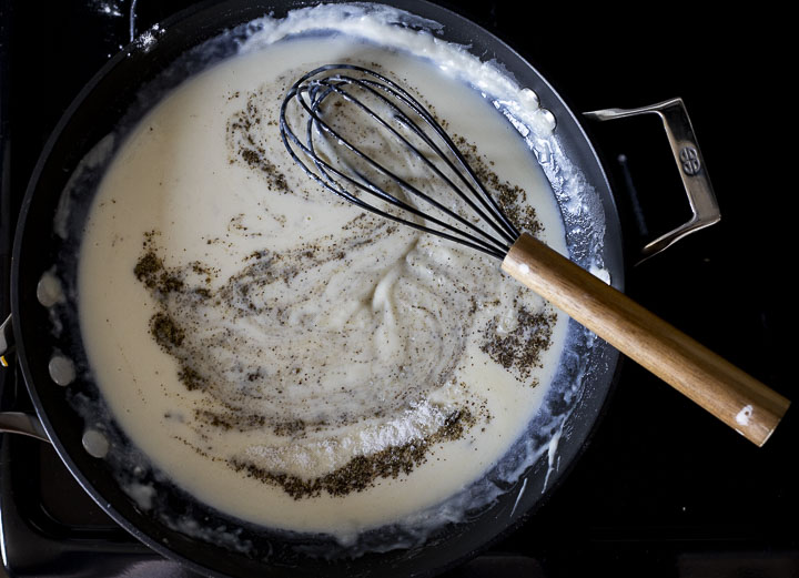 bechamel sauce with seasonings cooking in a skillet