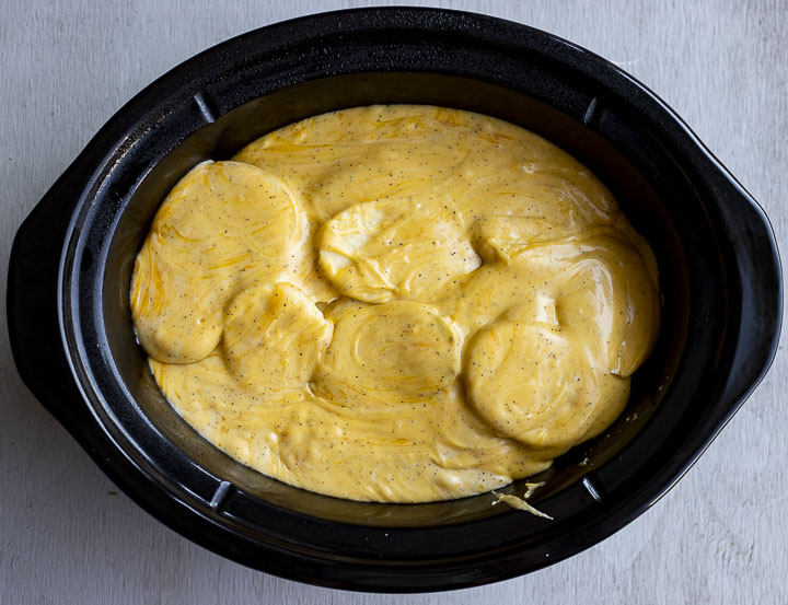 cheese sauce over sliced potatoes in a crock pot