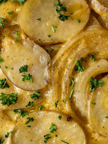 cheesy potatoes and sliced onions garnished with parsley