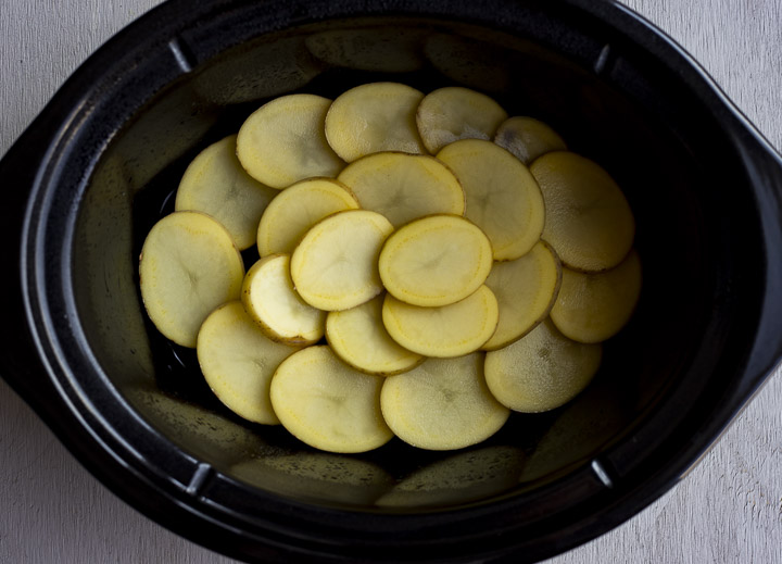 sliced potatoes layered in a crock pot