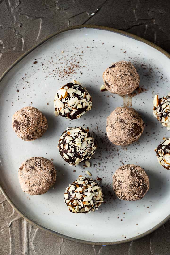 a plate of chocolate truffles rolled in nuts and cocoa powder