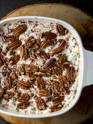 pecans on top of a creamy white dip in a baking dish