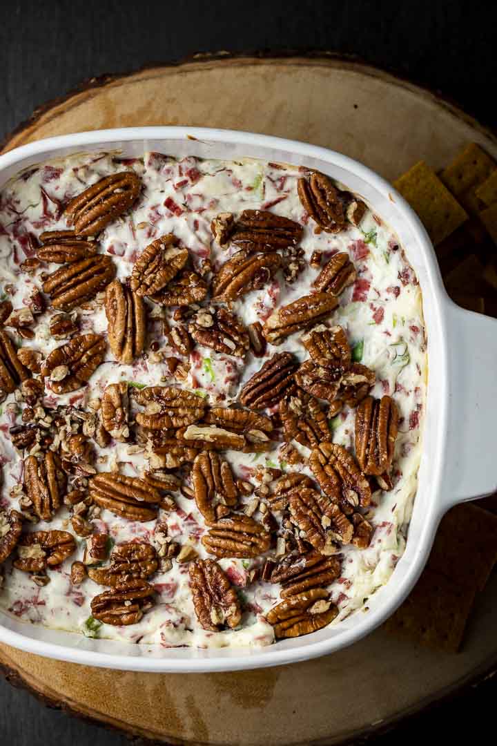 pecans on top of a creamy white dip in a baking dish