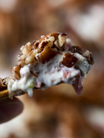 a cracker topped with white dip and pecans