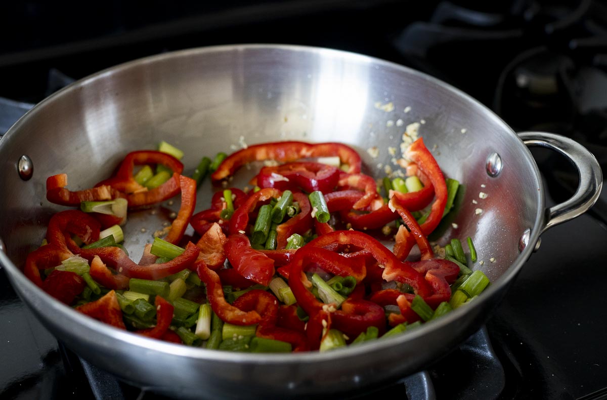 green onions and red pepper cooking in a skillet