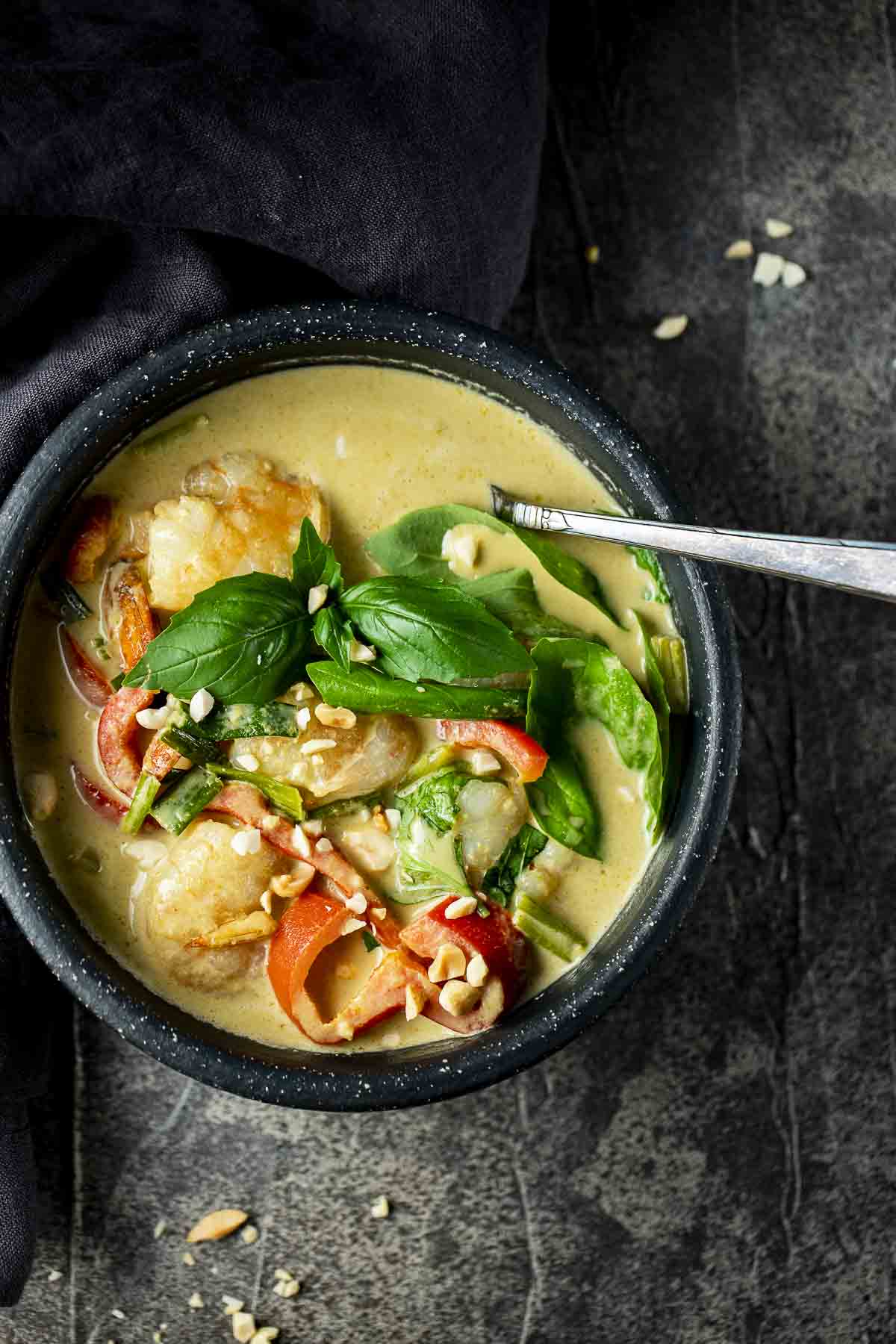 a bowl of curry shrimp and vegetables with a spoon
