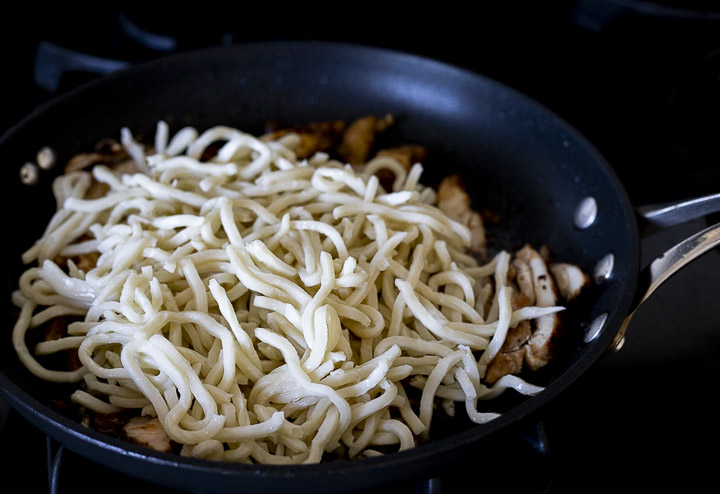 noodles being stir fried in a skillet