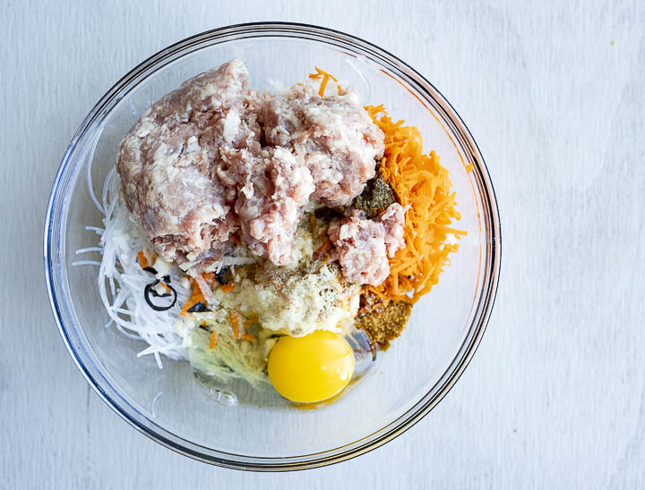 ground meat and vegetables in a bowl with a raw egg