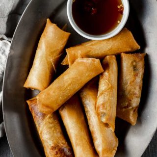 fried spring rolls on a plate with brown dipping sauce on the side