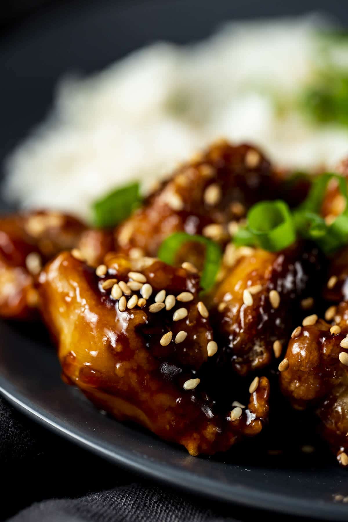 Close up of sesame chicken topped with sesame seeds.