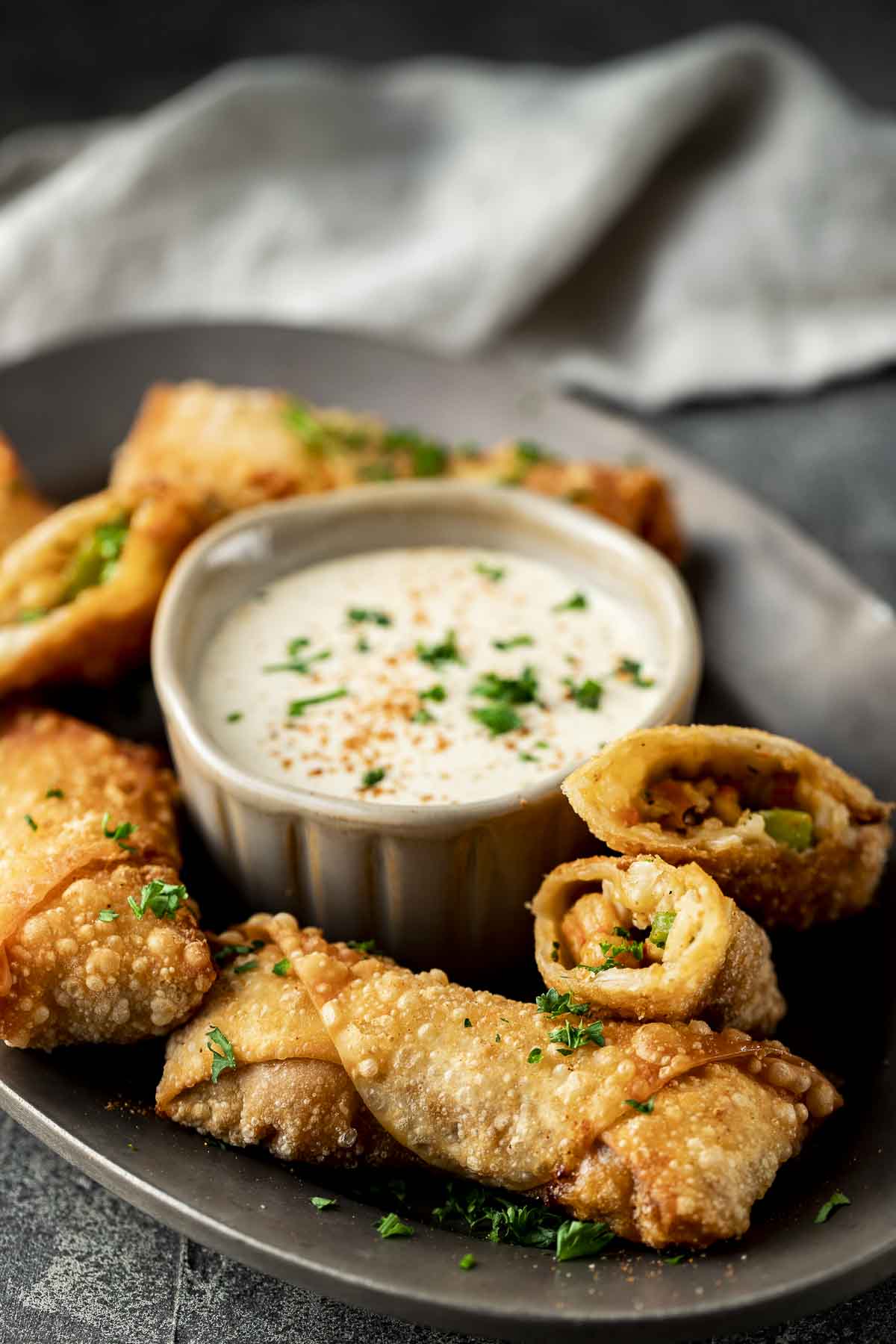 egg rolls on a plate around a bwol of white dipping sauce