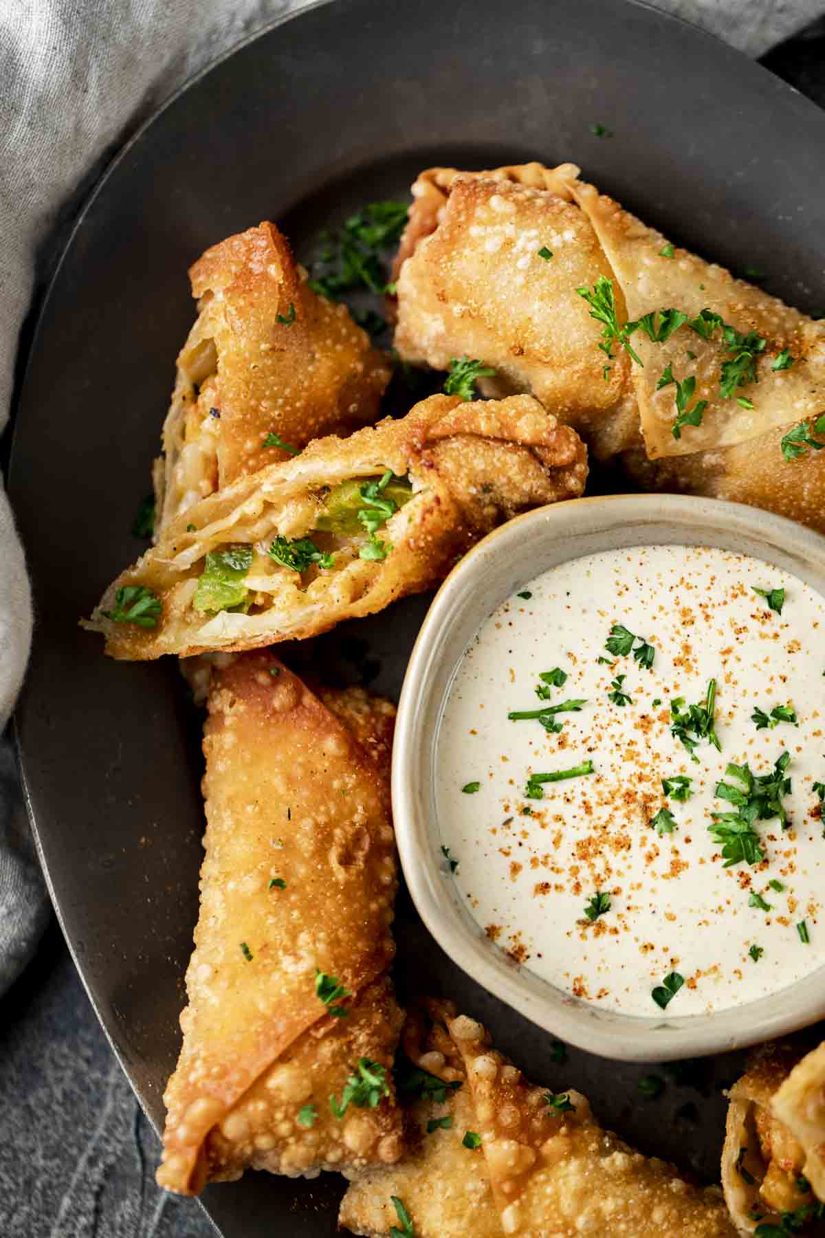 a platter of egg rolls with white cajun dipping sauce